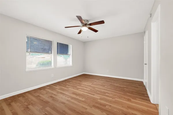 a view of empty room with wooden floor and fan