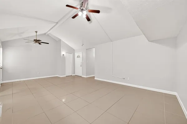 an empty room with chandelier fan and windows