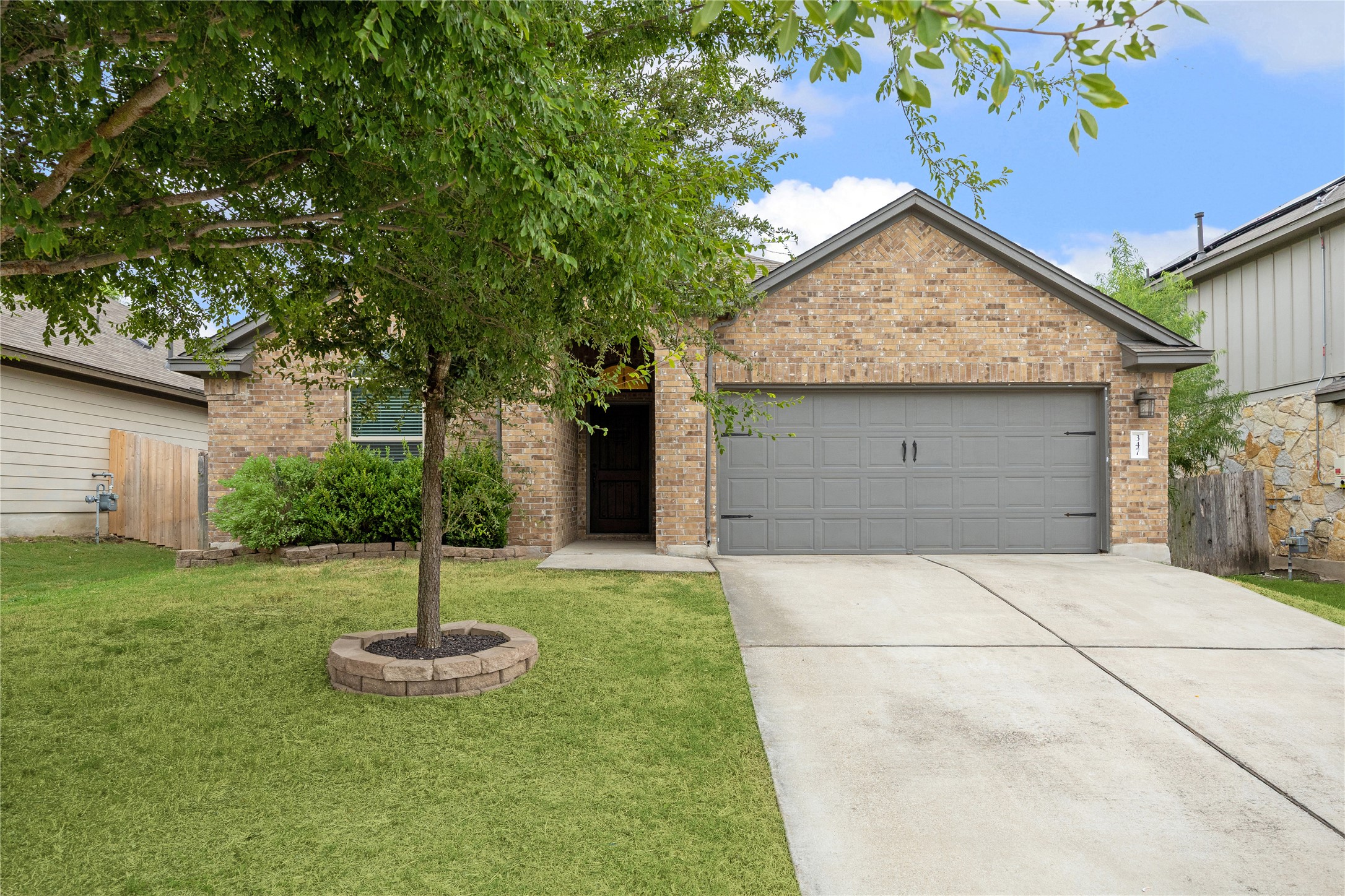 347 Noddy Road Buda, TX 78610 - Photo 1 of 1 View of front of property featuring a garage, brick siding, and concrete driveway