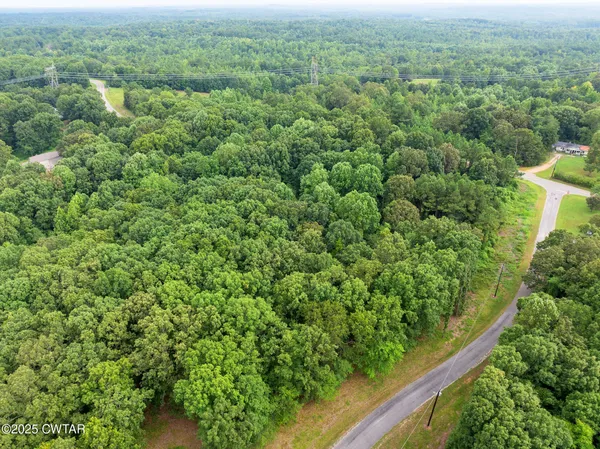 an aerial view of residential house with outdoor space and trees all around