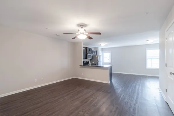 a view of a room with wooden floor and a ceiling fan