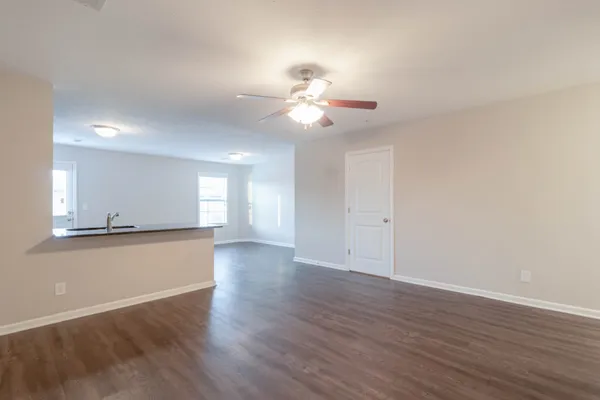 a view of an empty room with window and wooden floor