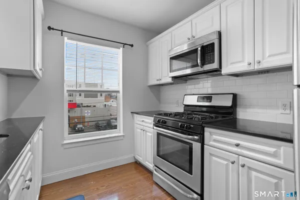 a kitchen with stainless steel appliances granite countertop white cabinets and window