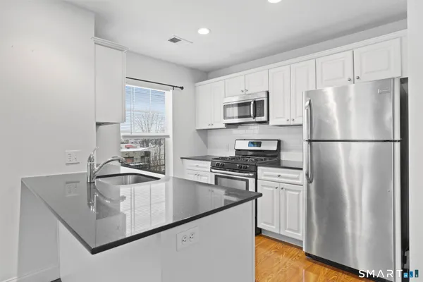 a kitchen with granite countertop a refrigerator stove and sink
