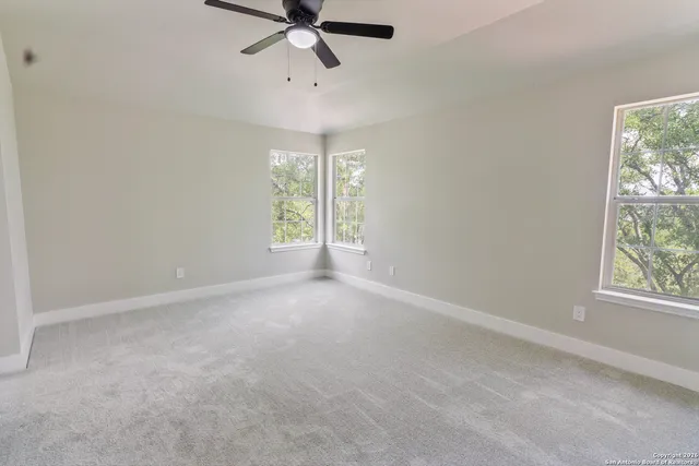 en empty room with windows and chandelier fan