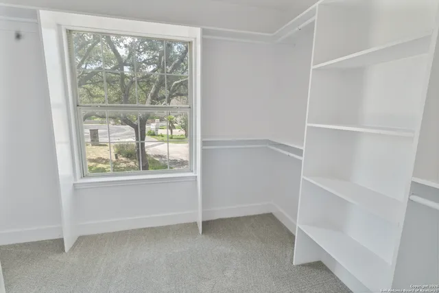 an empty room with windows and ceiling fan
