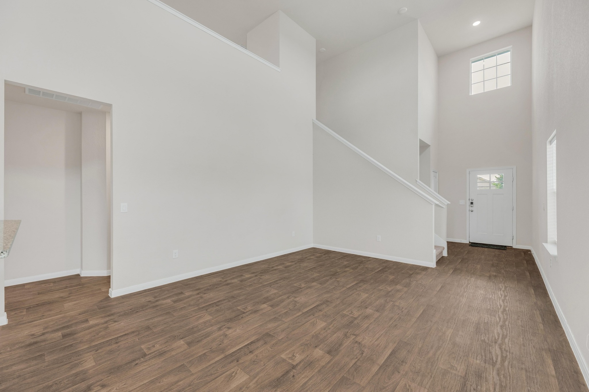 2900 Tweedy Trail Pflugerville, TX 78660 - Photo 2 of 33 Unfurnished living room with a high ceiling, dark wood-style flooring, baseboards, stairway, and recessed lighting
