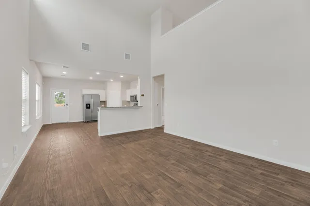 a view of a big room with wooden floor and kitchen view