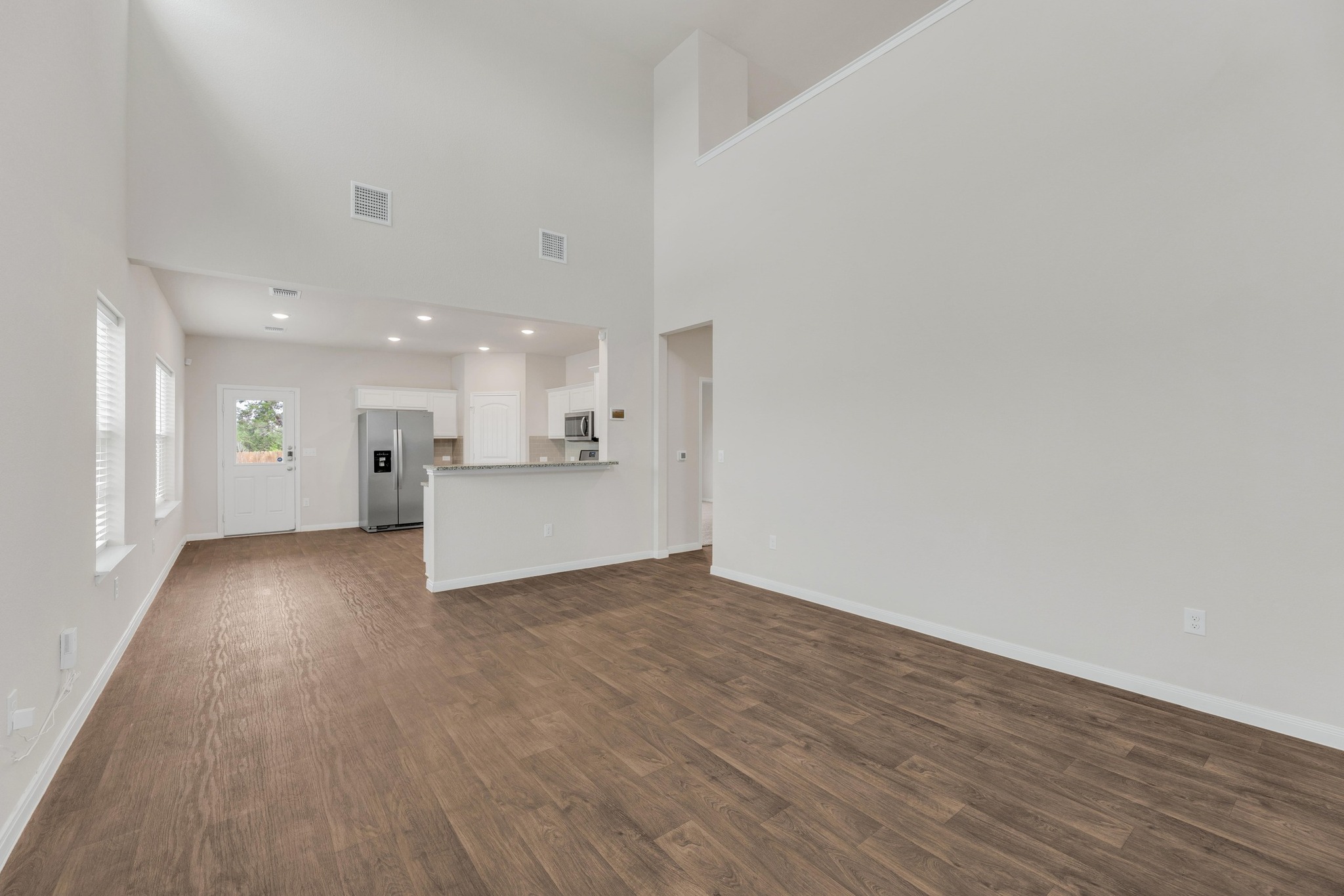 2900 Tweedy Trail Pflugerville, TX 78660 - Photo 5 of 33 Unfurnished living room featuring dark wood finished floors, baseboards, and a towering ceiling