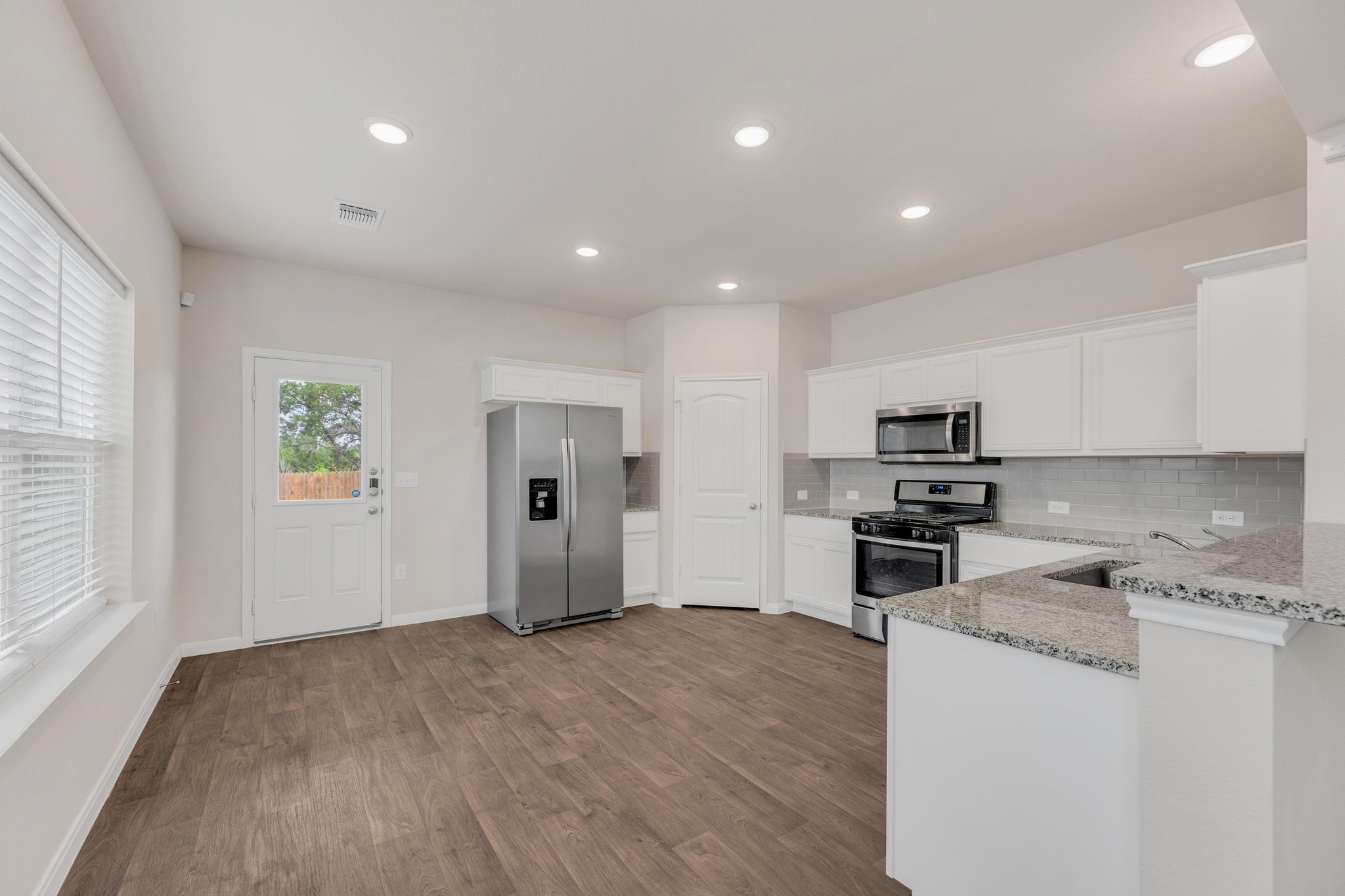 2900 Tweedy Trail Pflugerville, TX 78660 - Photo 6 of 33 Kitchen with appliances with stainless steel finishes, light stone countertops, backsplash, dark wood-style flooring, and white cabinets