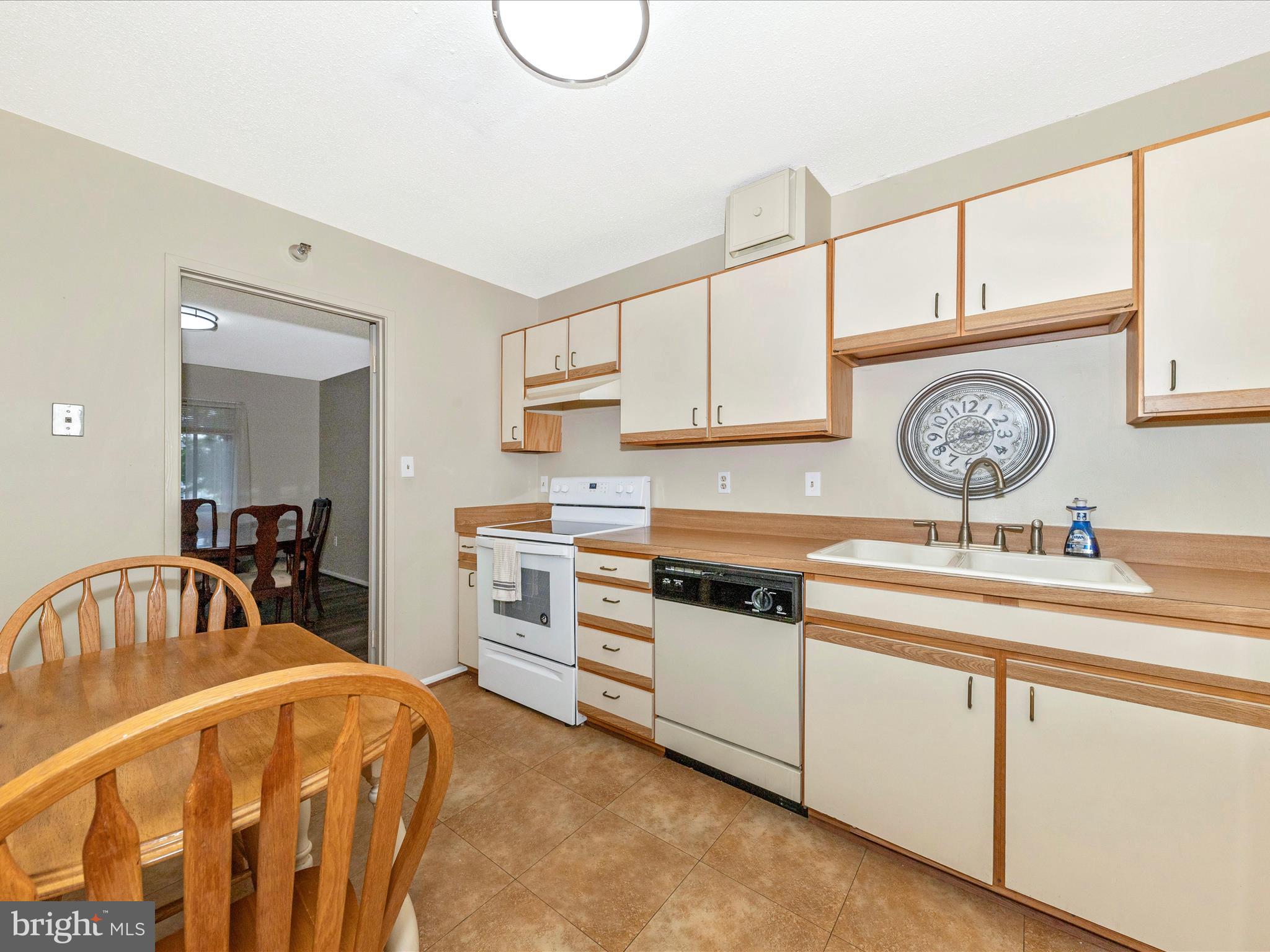 15101 Interlachen Drive, Unit 1116 Silver Spring, MD 20906 - Photo 21 of 78 a white kitchen with a stove a sink and a table with chairs