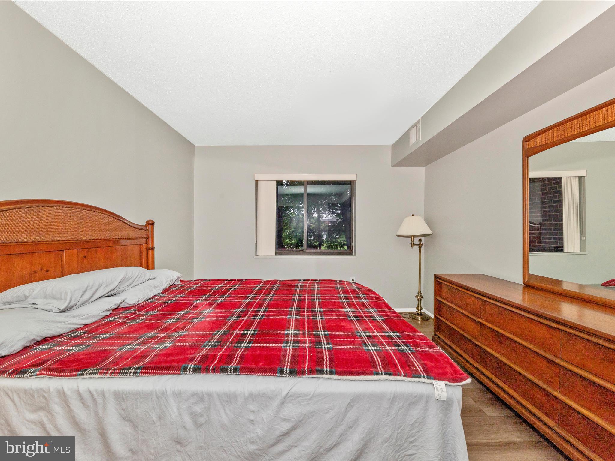 15101 Interlachen Drive, Unit 1116 Silver Spring, MD 20906 - Photo 25 of 78 a bedroom with a large bed and a lamp