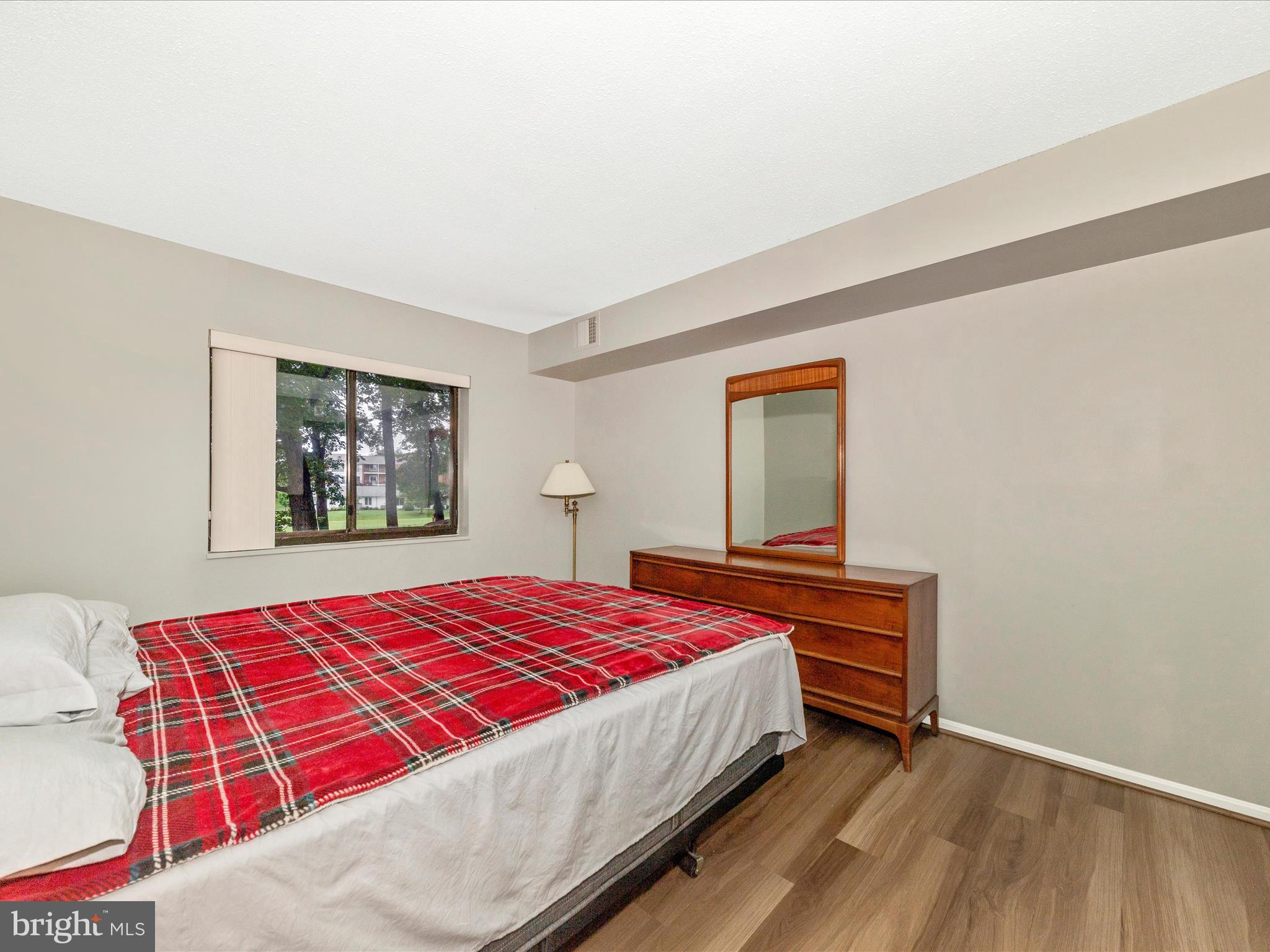 15101 Interlachen Drive, Unit 1116 Silver Spring, MD 20906 - Photo 26 of 78 a bedroom with a bed and dresser with wooden floor