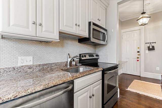 a kitchen with stainless steel appliances granite countertop a sink dishwasher stove and microwave with wooden floor