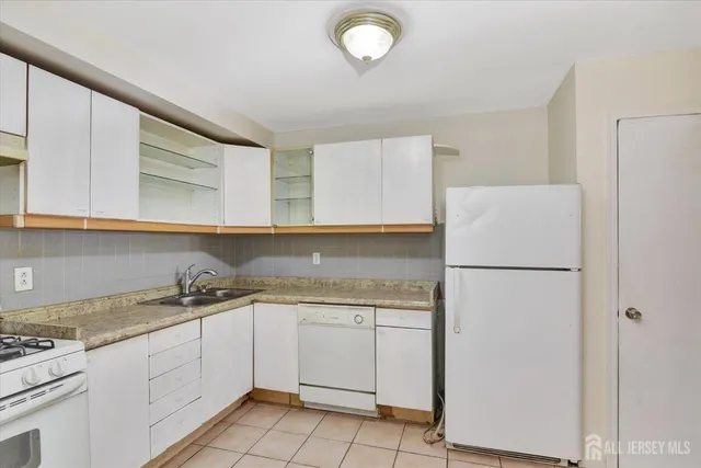 a kitchen with a sink a refrigerator and cabinets