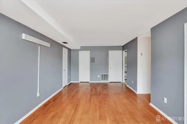 a view of a big room with wooden floor and windows