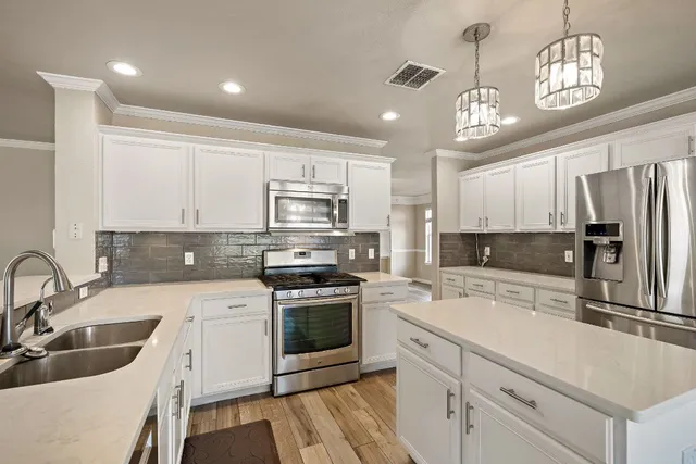 a kitchen with a sink stainless steel appliances cabinets and a window