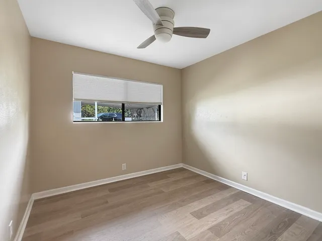 an empty room with a window and a ceiling fan