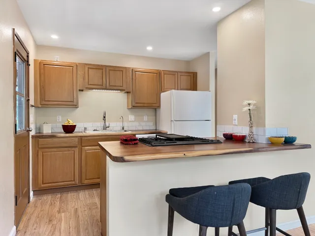a kitchen with stainless steel appliances granite countertop a sink a stove a refrigerator a microwave oven with white cabinets and wooden floor