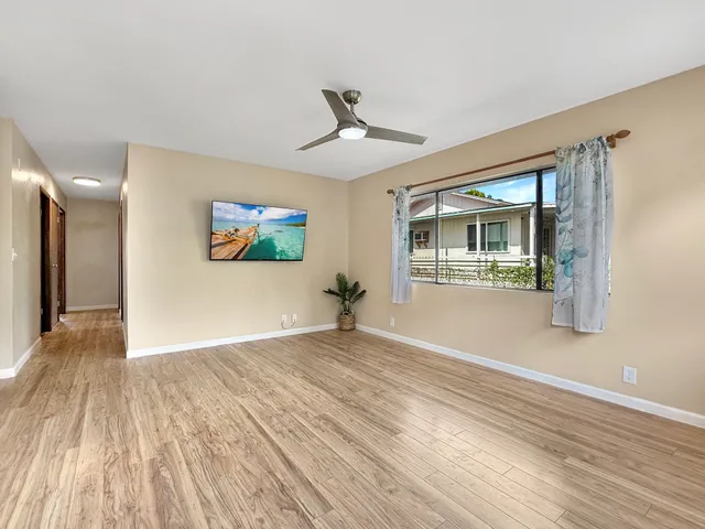 a view of empty room with wooden floor and fan