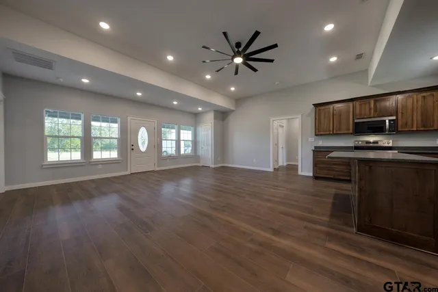 an empty room with wooden floor and a kitchen