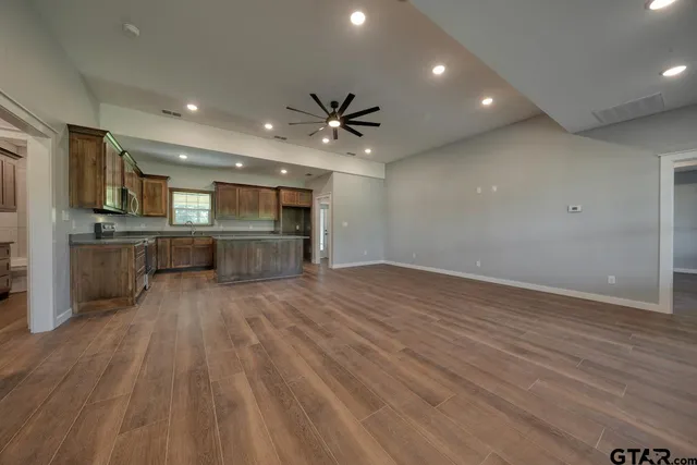 a kitchen with stainless steel appliances granite countertop wooden cabinets a sink and dishwasher with wooden floor