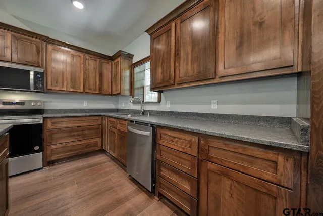 a kitchen with granite countertop a sink a stove and cabinets