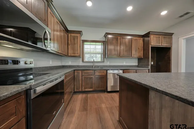 a kitchen with stainless steel appliances granite countertop a stove a sink and a refrigerator