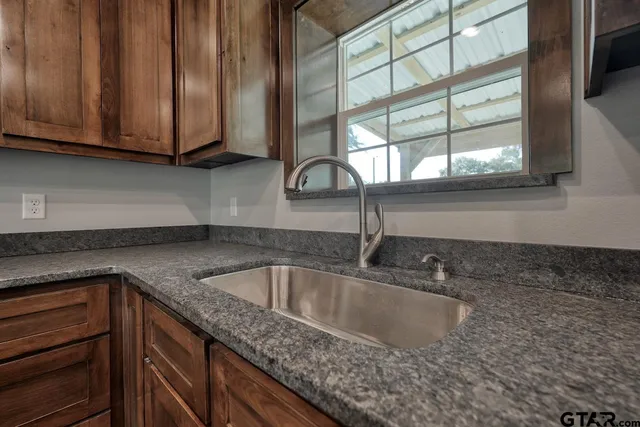 a kitchen with stainless steel appliances granite countertop wooden cabinets and a stove top oven