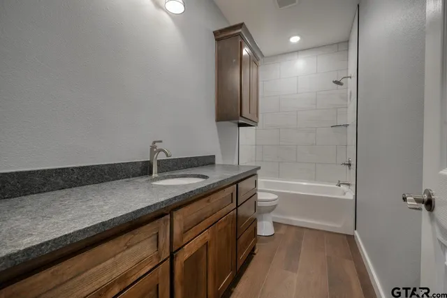 an empty room with wooden floor chandelier fan and windows