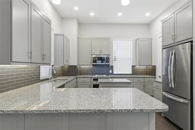 a kitchen with stainless steel appliances granite countertop a sink a stove and a refrigerator