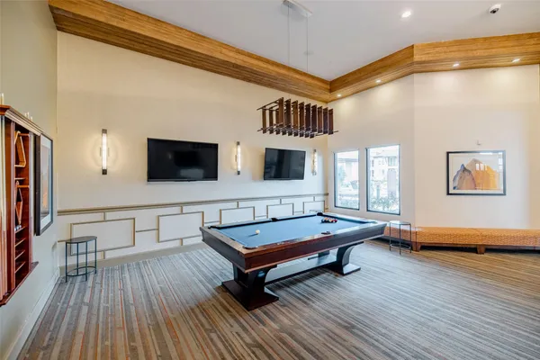 a living room with pool table flat screen tv and wooden floor