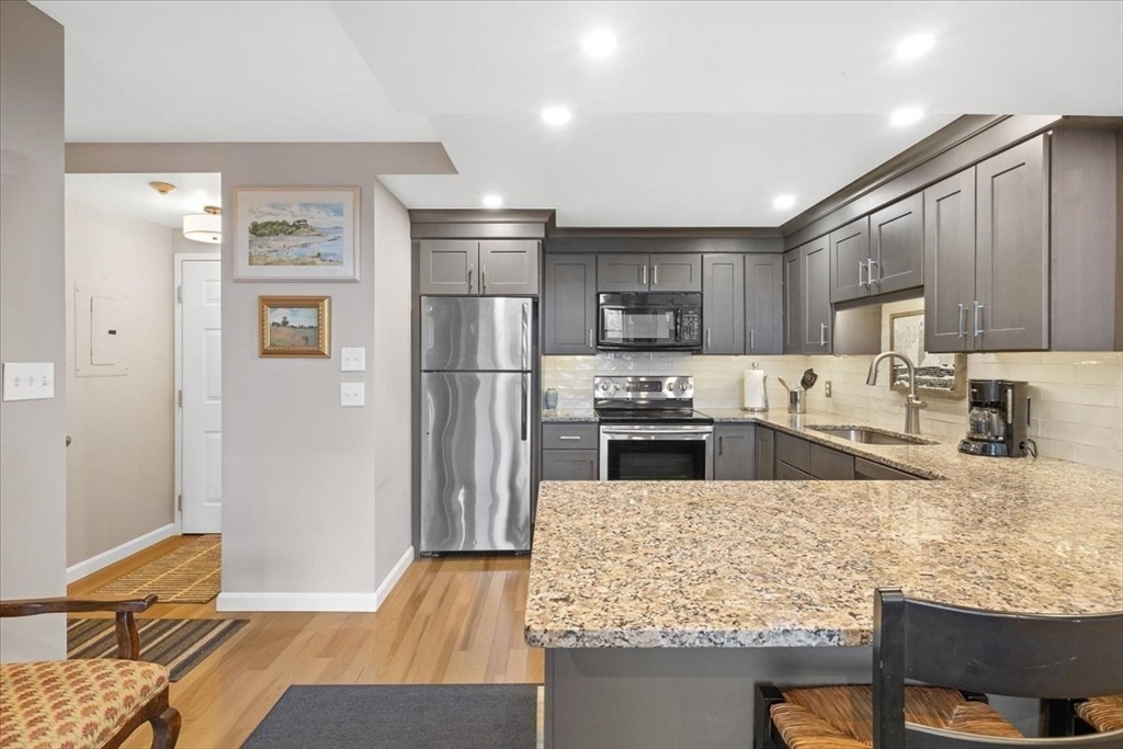 155 George Washington Boulevard, Unit 707 Hull, MA 02045 - Photo 12 of 24 a kitchen with granite countertop a refrigerator and a stove top oven