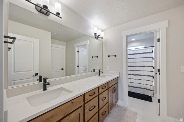 754 West 400 North, Unit 29 Mapleton, UT 84664 - Photo 17 of 25 Full bathroom with a shower with shower curtain, double vanity, a textured ceiling, and light marble finish flooring