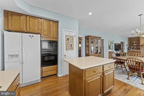 a kitchen with a refrigerator a stove and a dining table with wooden floor
