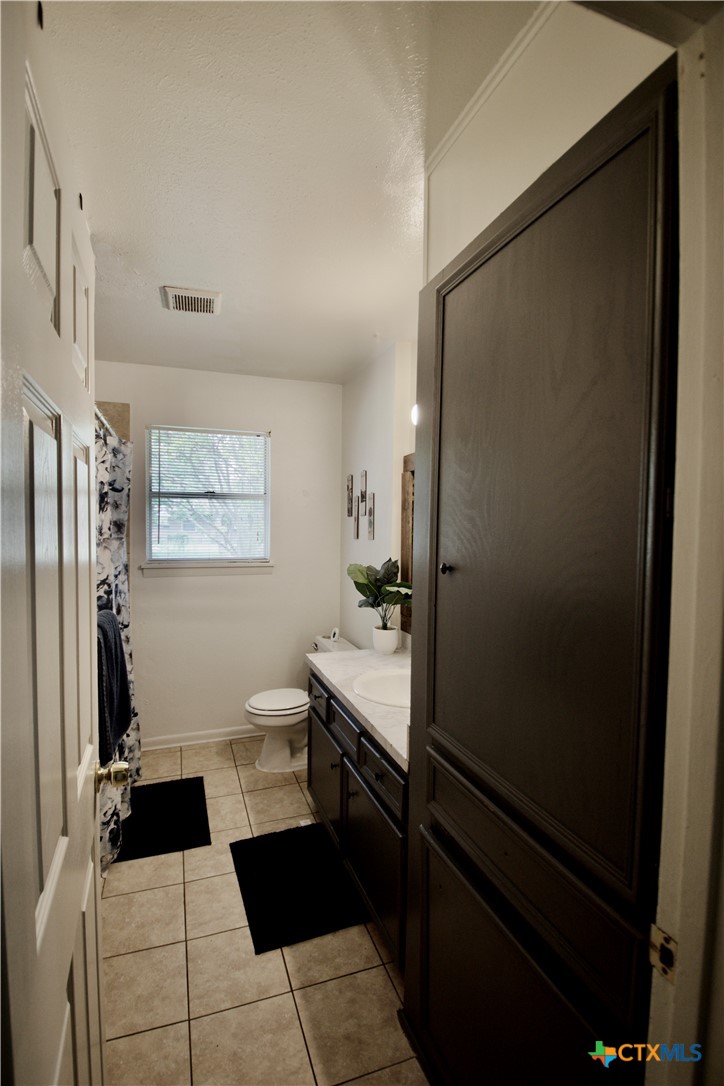 1411 West Lane Killeen, TX 76549 - Photo 14 of 36 a bathroom with a sink a toilet a mirror and shower