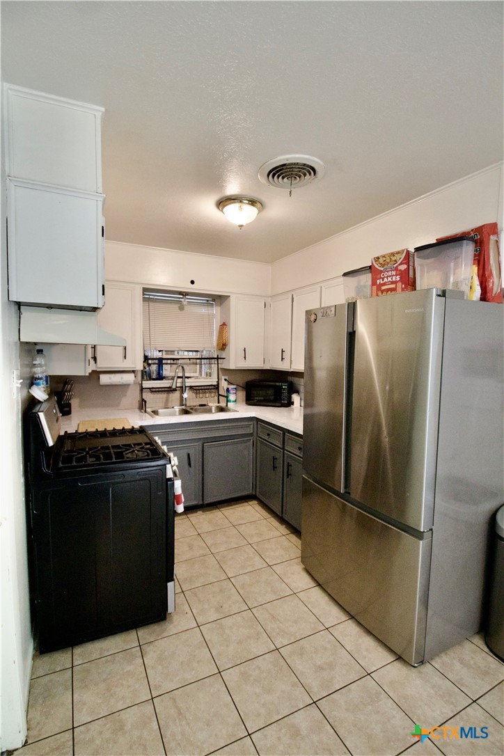 1411 West Lane Killeen, TX 76549 - Photo 9 of 36 a kitchen with a refrigerator sink and cabinets
