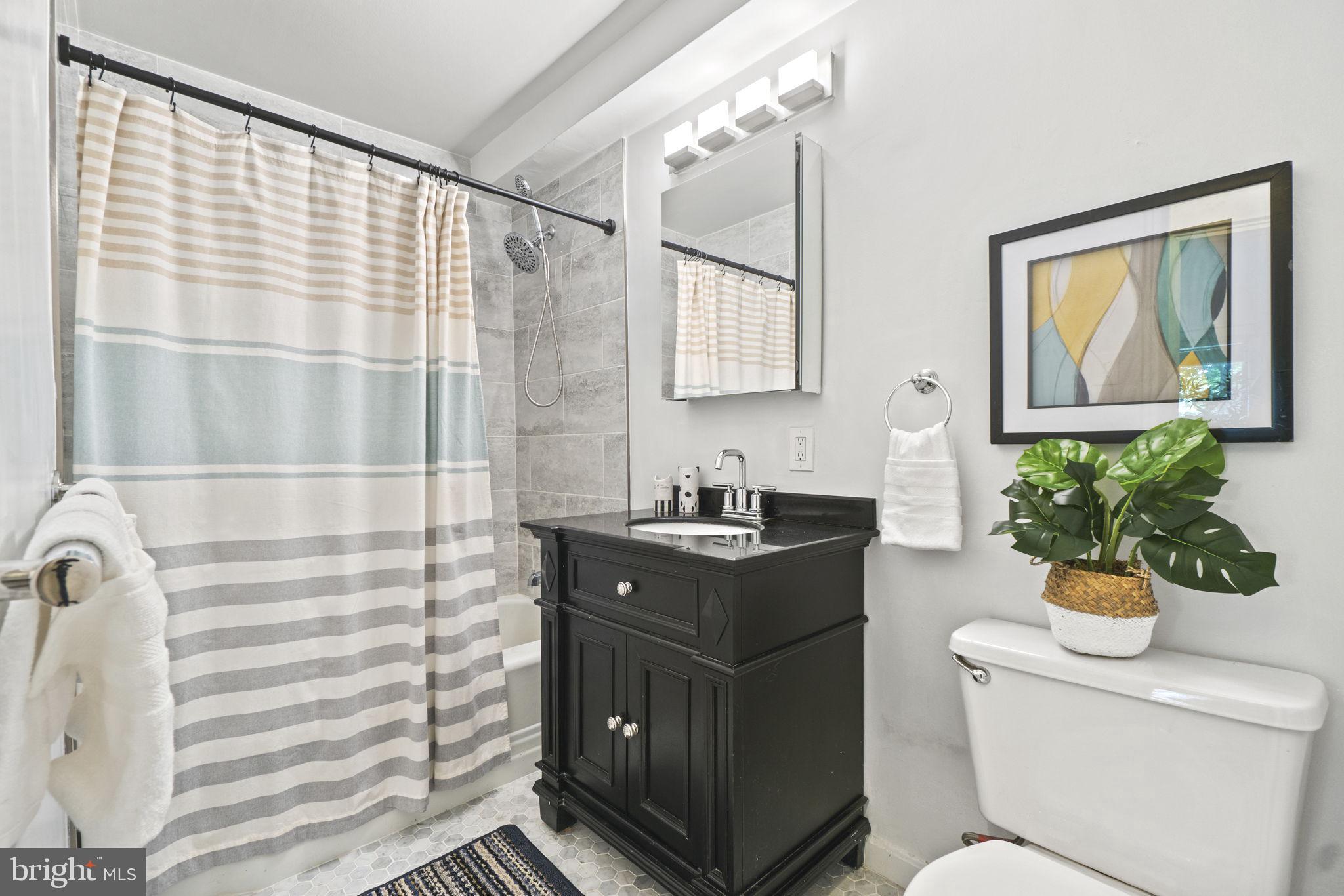 2500 Q Street Northwest, Unit 206 Washington, DC 20007 - Photo 8 of 21 a bathroom with a granite countertop sink a mirror a vanity and a shower