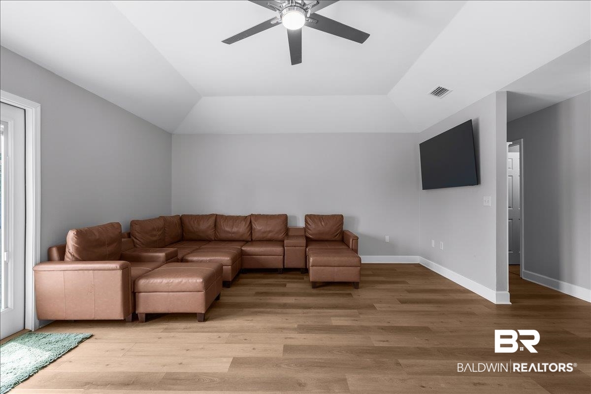 8952 Sherman Road Foley, AL 36535 - Photo 11 of 41 Spacious living area featuring wood-finish flooring, a vaulted ceiling, and a ceiling fan