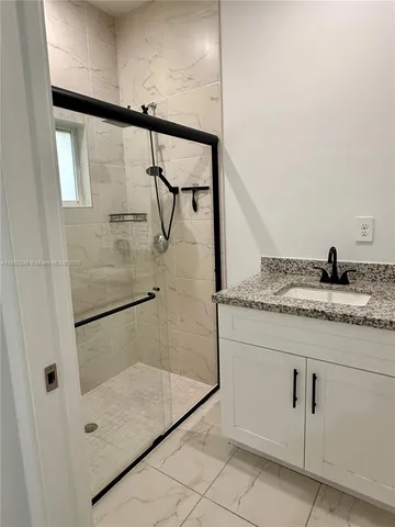 a bathroom with a granite countertop sink a mirror and shower