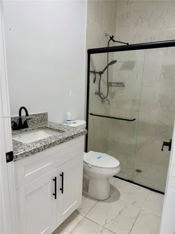 a bathroom with a granite countertop sink toilet and shower