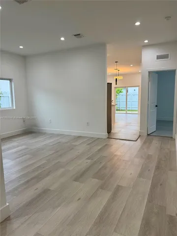 an empty room with wooden floor and a bathroom