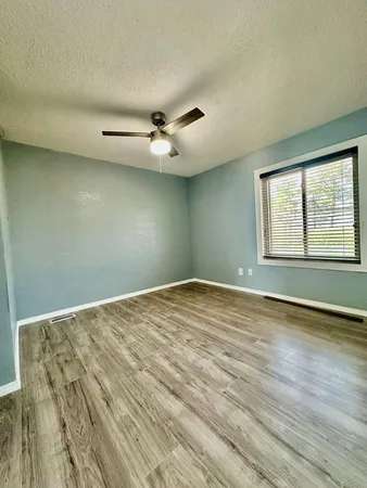 an empty room with wooden floor fan and windows