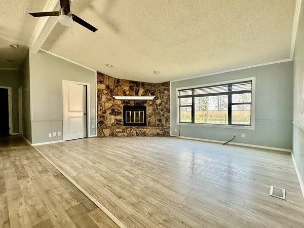 a view of empty room with a fireplace and wooden floor