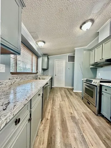 a kitchen with granite countertop a sink stove and cabinets