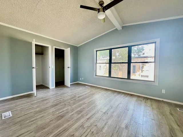 an empty room with wooden floor chandelier and windows