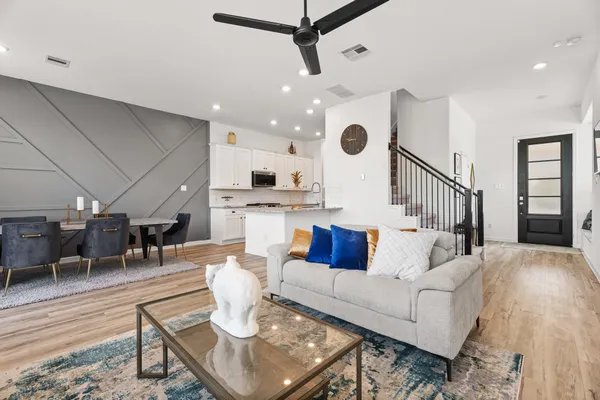 a living room with furniture kitchen view and a wooden floor
