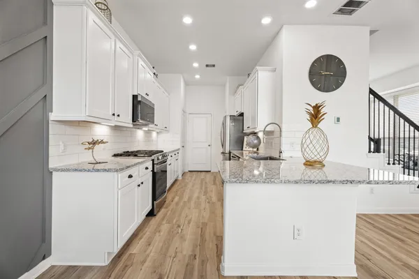 a kitchen with kitchen island granite countertop a white cabinets a stove and a sink