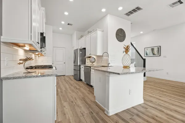 a kitchen with stainless steel appliances granite countertop a sink a stove and a wooden floors