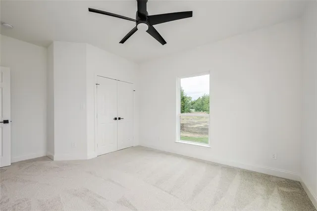 an empty room with a window and a fan